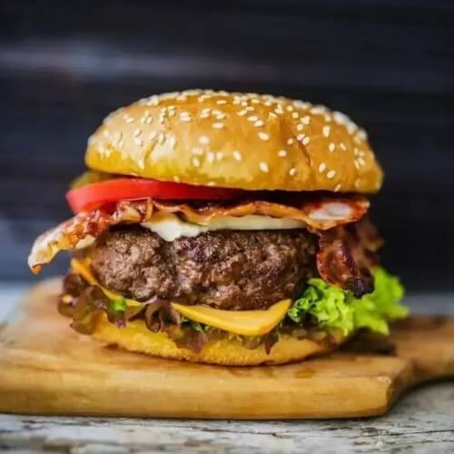 large beef burger on cutting board