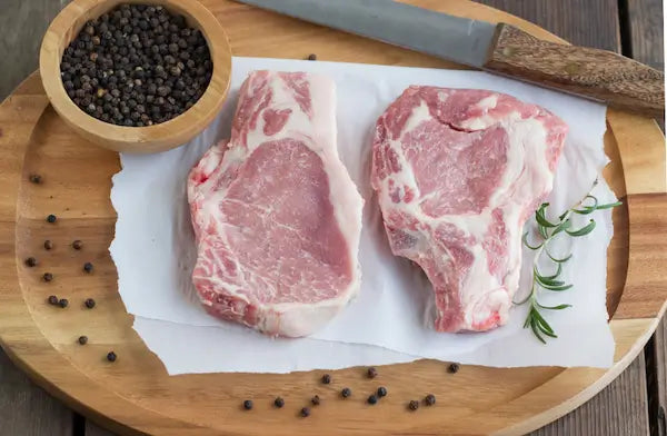 pork chops on cutting board with peppercorn and knife